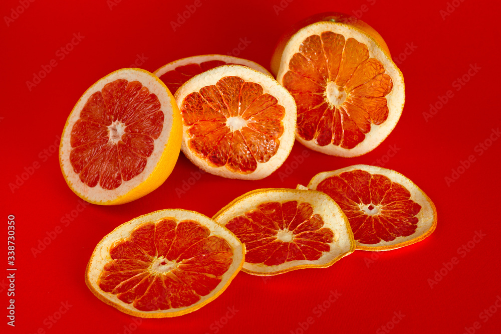 Chips of dried grapefruit sliced in thin circles, shot on a red background. Background for vegetarianism, healthy and wholesome food. Chips of dried grapefruit sliced in thin circles, shot on a red background. Background for vegetarianism, healthy and wholesome food.