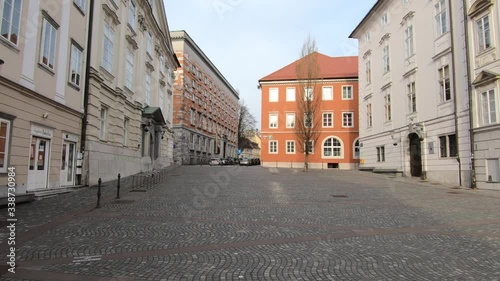 Bike ride through Ljubljana city downtown streets and square on workday, Slovenia. Coronavirus COVID 19 quarantine pandemic lockdown restrictions. Forward dolly moving, wide shot