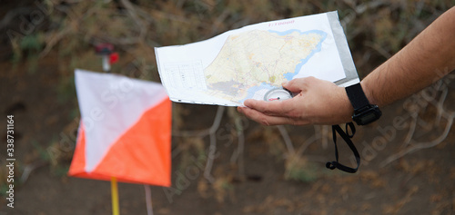 Man holding map.Athlete uses navigation equipment for orienteering,compass and topographic map 