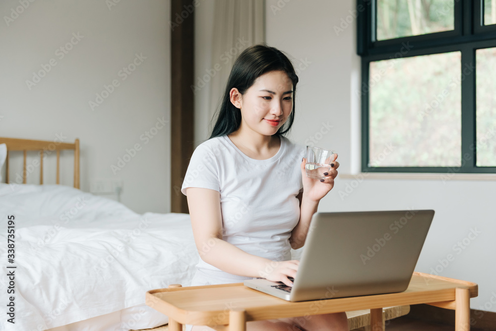 Young Asian girl using laptop in bed