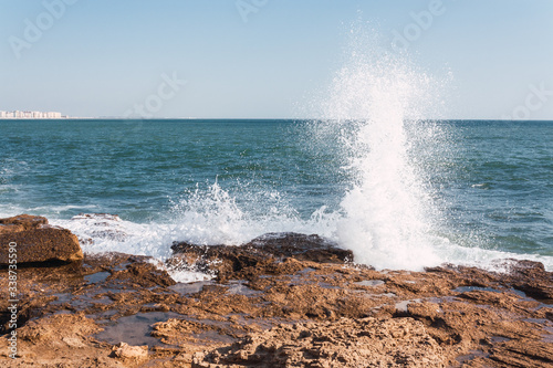 A wave hits the rocks with the Atlantic Ocean behind it.