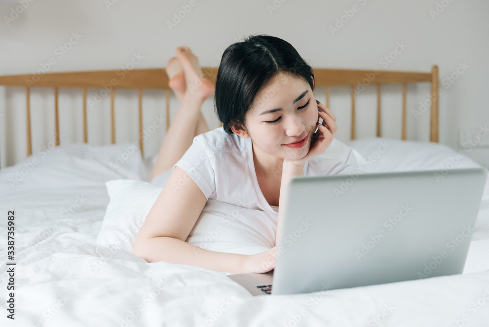 Young Asian girl using laptop in bed Young Asian girl using laptop in bed