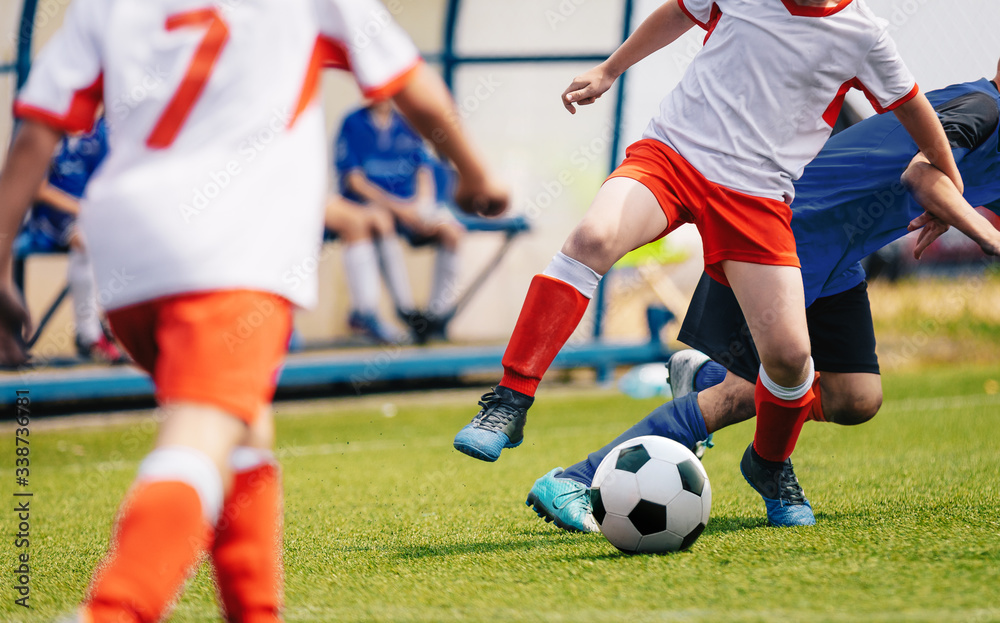 Young Soccer Players Competition. Boys Kicking Football Ball. Soccer Youth Teams Play Outdoor Tournament. Soccer Stadium and Bench in the Background Young Soccer Players Competition. Boys Kicking Football Ball. Soccer Youth Teams Play Outdoor Tournament. Soccer Stadium and Bench in the Background