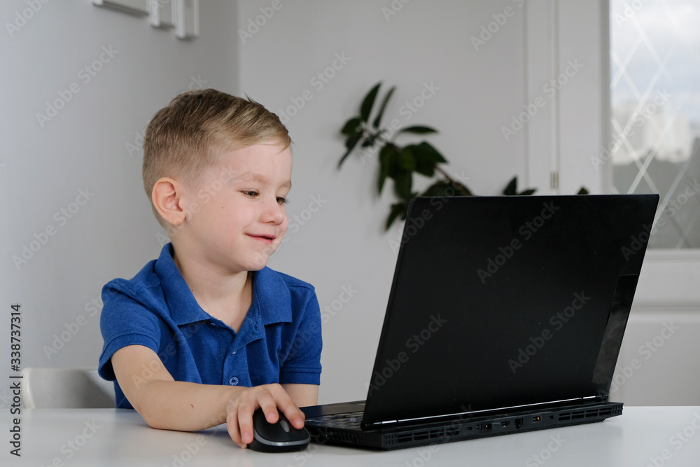 Little boy sit a home during quarantine and study in the internet school using a computer. Little boy sit a home during quarantine and study in the internet school using a computer.