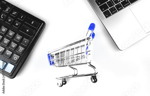 shopping cart, trolley with calculator and laptop keyboard closeup. Online shopping