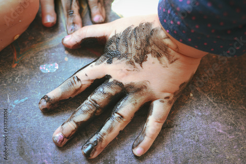 The child got his hands dirty in black nail polish. Hands of the baby in black paint. Baby draws with hands