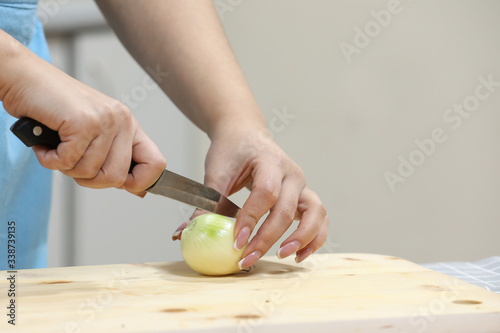 Young woman cooking in kitchen. Housewife preparing vegetables for cooking. Peel onion. Cooking soup