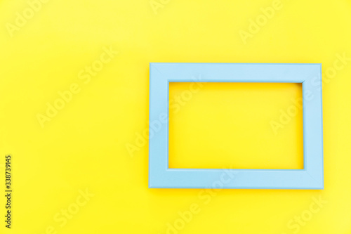 Simply design with empty blue frame isolated on yellow colourful trendy background. Top view, flat lay, copy space, mock up. Minimal concept.