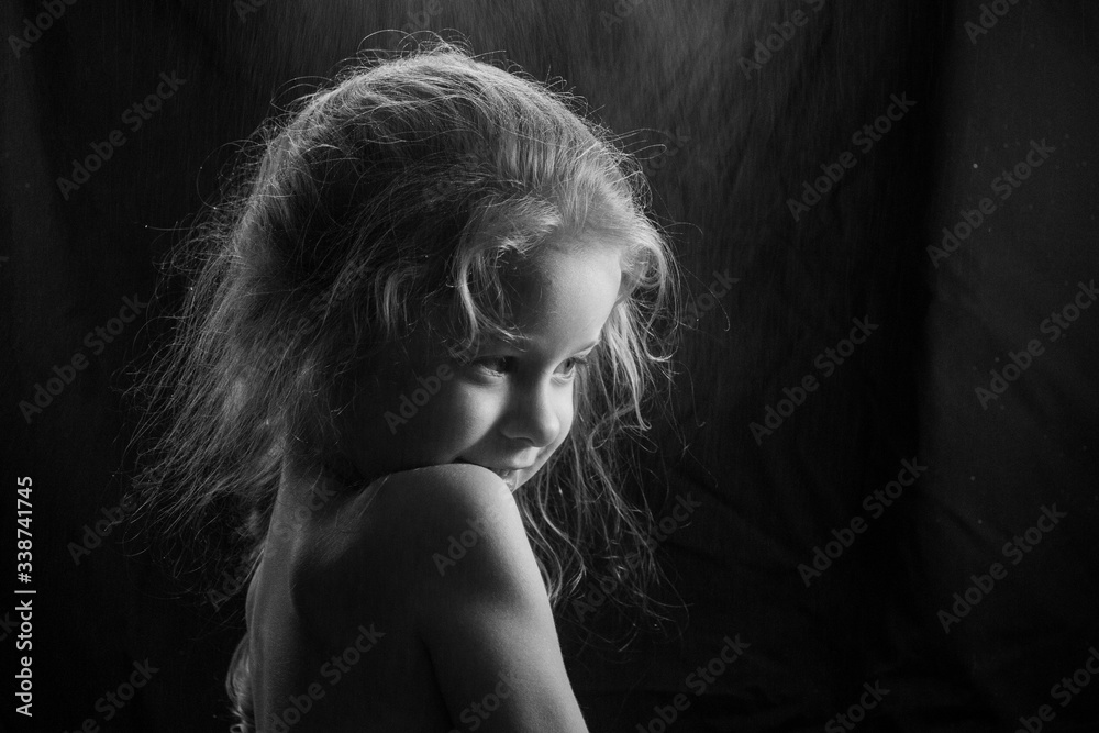 black and white frame: portrait of a little girl under the spray on a black background
