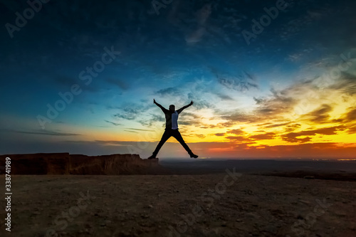 Happy Man jumping silhoutte poses with beautiful sunset background in Edge of the world Riyadh Saudi Arabia. Selective focused on the subject.