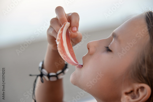Close up girl eating a piece of jamon