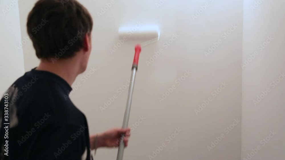 Worker painting walls with white paint Worker painting walls with white paint