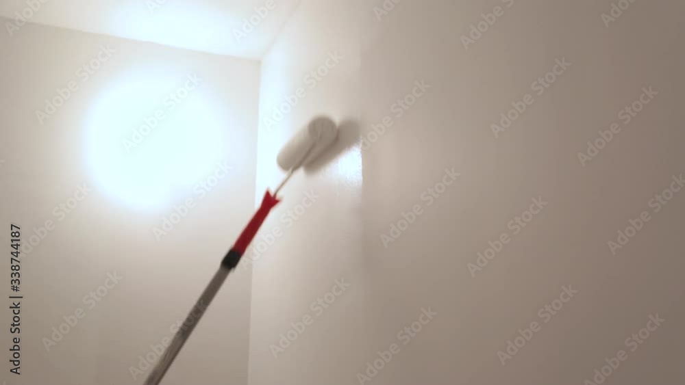 Worker painting walls with white paint Worker painting walls with white paint