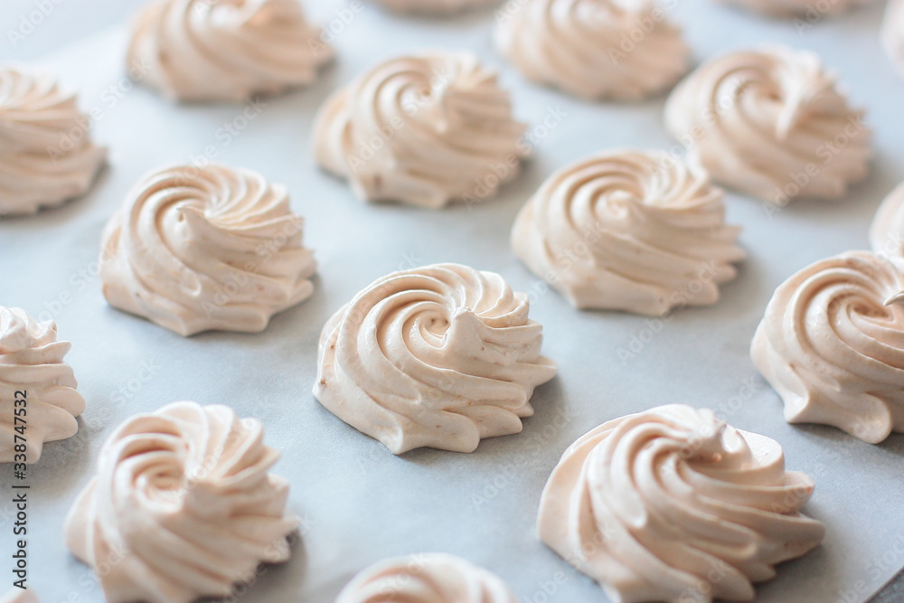Many fresh (just made) marshmallow roses (zephyrs) in lines on cooking paper Many fresh (just made) marshmallow roses (zephyrs) in lines on cooking paper