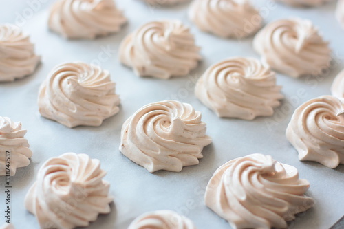 Many fresh (just made) marshmallow roses (zephyrs) in lines on cooking paper