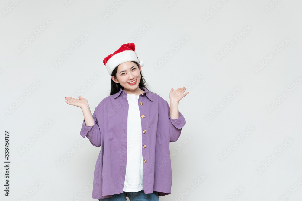 A young asian woman in a Christmas hat stands in front of the white wall A young asian woman in a Christmas hat stands in front of the white wall