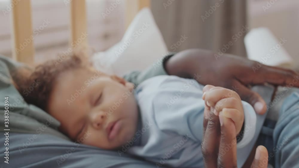 Close up of mixed-race sweet kid sleeping on his father. African male hands patting sleeping infant Close up of mixed-race sweet kid sleeping on his father. African male hands patting sleeping infant