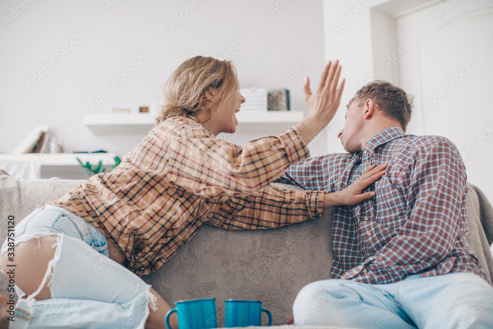 Unhappy young millennial married couple sitting on couch in living room at home and quarrelling. Husband arguing emotionally talking frustrated wife looking away. Break up and misunderstanding concept Unhappy young millennial married couple sitting on couch in living room at home and quarrelling. Husband arguing emotionally talking frustrated wife looking away. Break up and misunderstanding concept