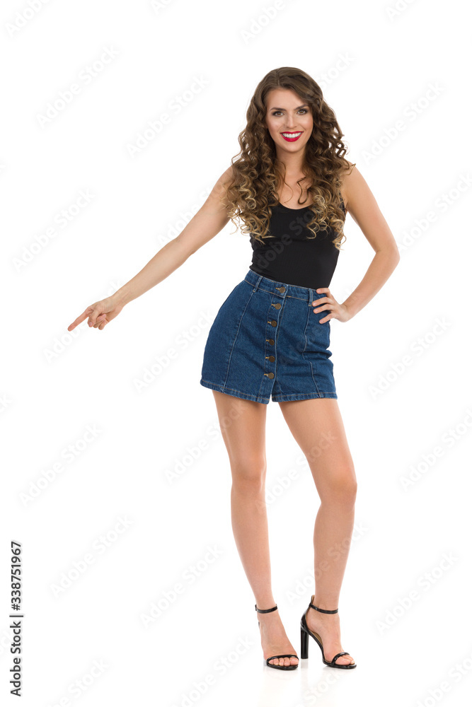 Young Confident Woman In Jeans Mini Skirt And High Heels Is Pointing Down Young Confident Woman In Jeans Mini Skirt And High Heels Is Pointing Down