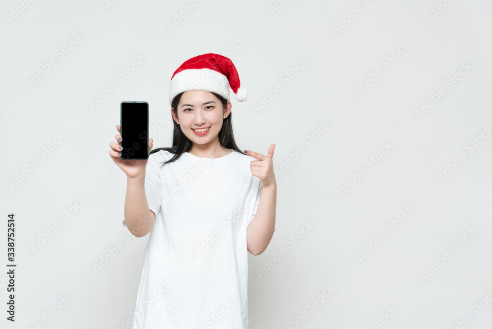 A young asian woman in a Christmas hat stands in front of the white wall A young asian woman in a Christmas hat stands in front of the white wall