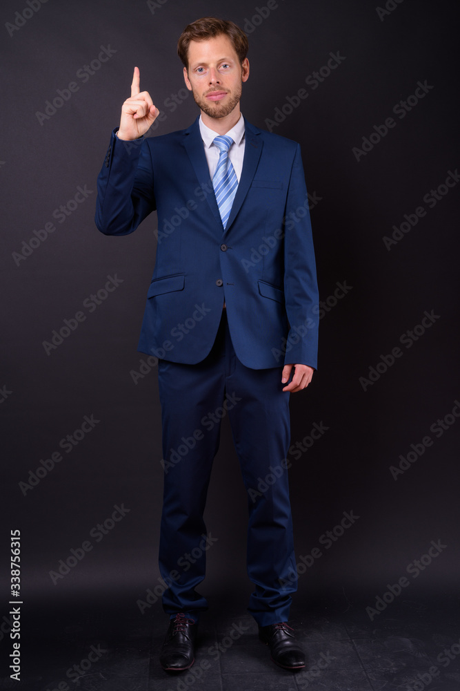 Full body shot of bearded businessman in suit pointing up Full body shot of bearded businessman in suit pointing up