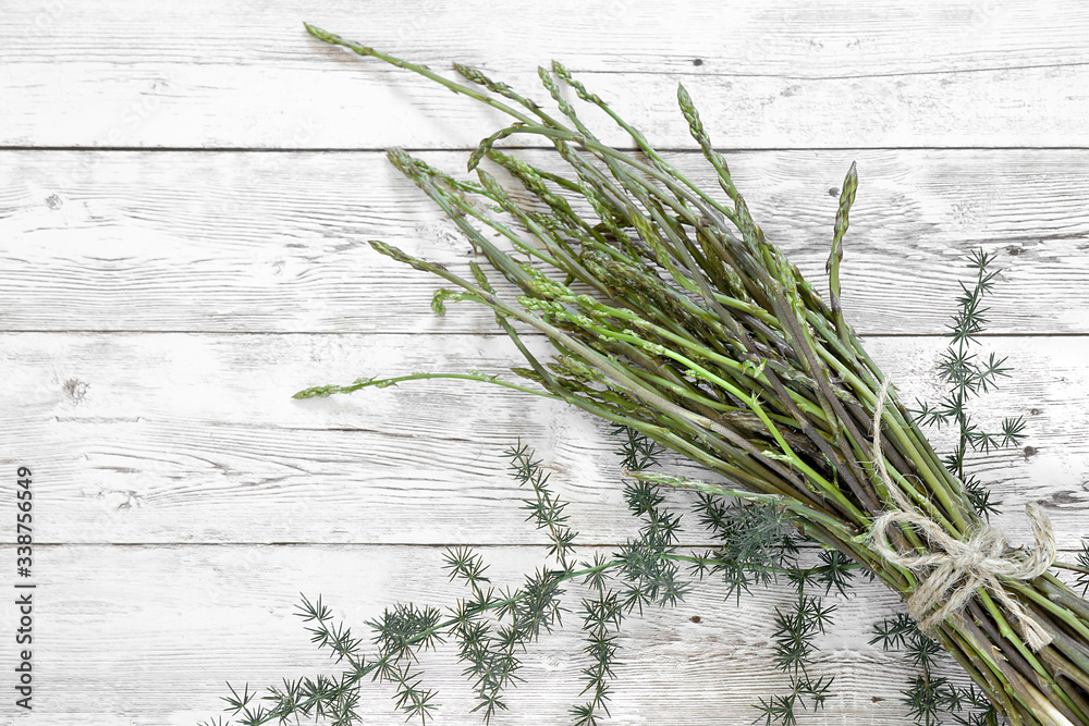 bunch of fresh wild asparagus plant and leaves on a wooden table. bunch of fresh wild asparagus plant and leaves on a wooden table.