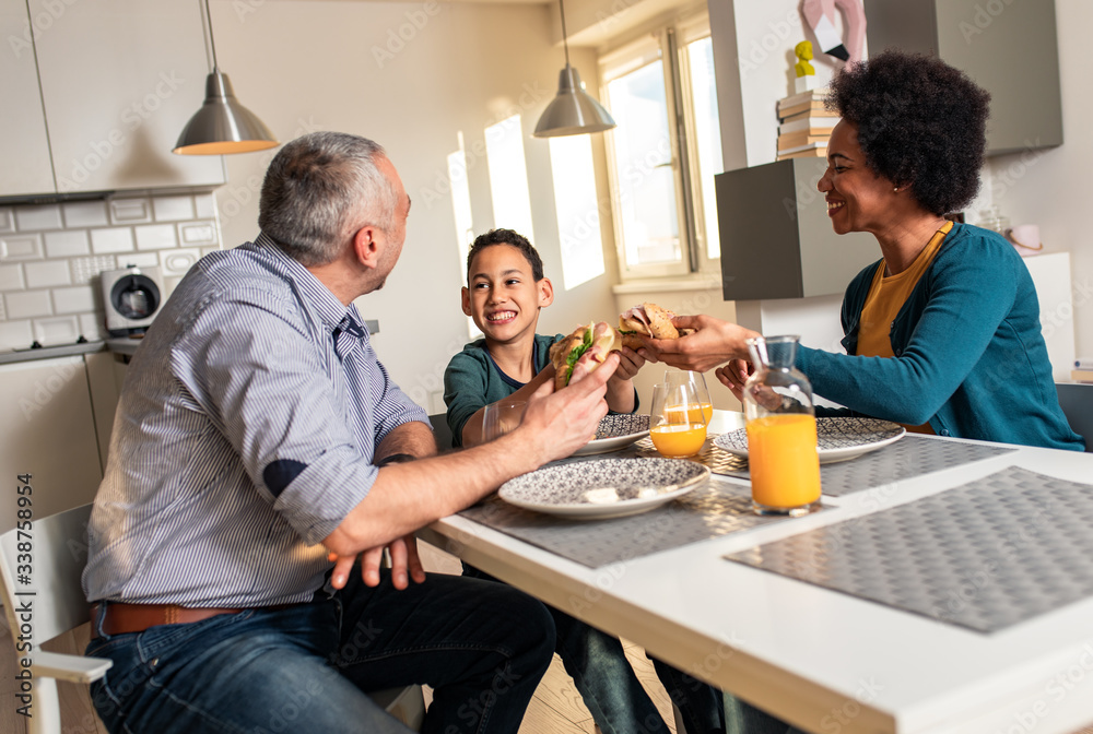 Smiling mixed race family with they son sitting at the kitchen table having breakfast at home. Smiling mixed race family with they son sitting at the kitchen table having breakfast at home.