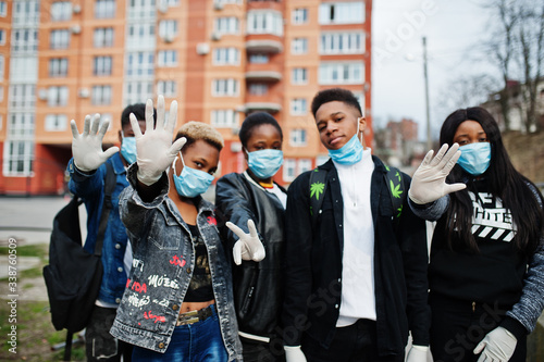 Group of african teenagers friends against empty street with building wearing medical masks protect from infections and diseases coronavirus virus quarantine.
