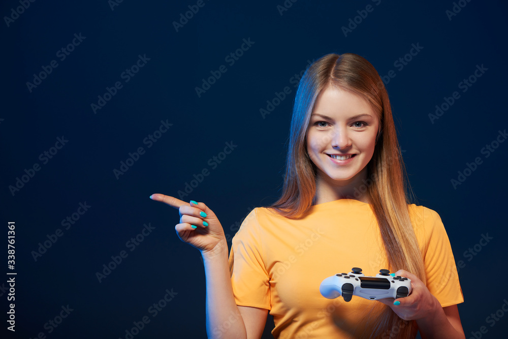 Happy girl holding video game joystick pointing finger to side Happy girl holding video game joystick pointing finger to side
