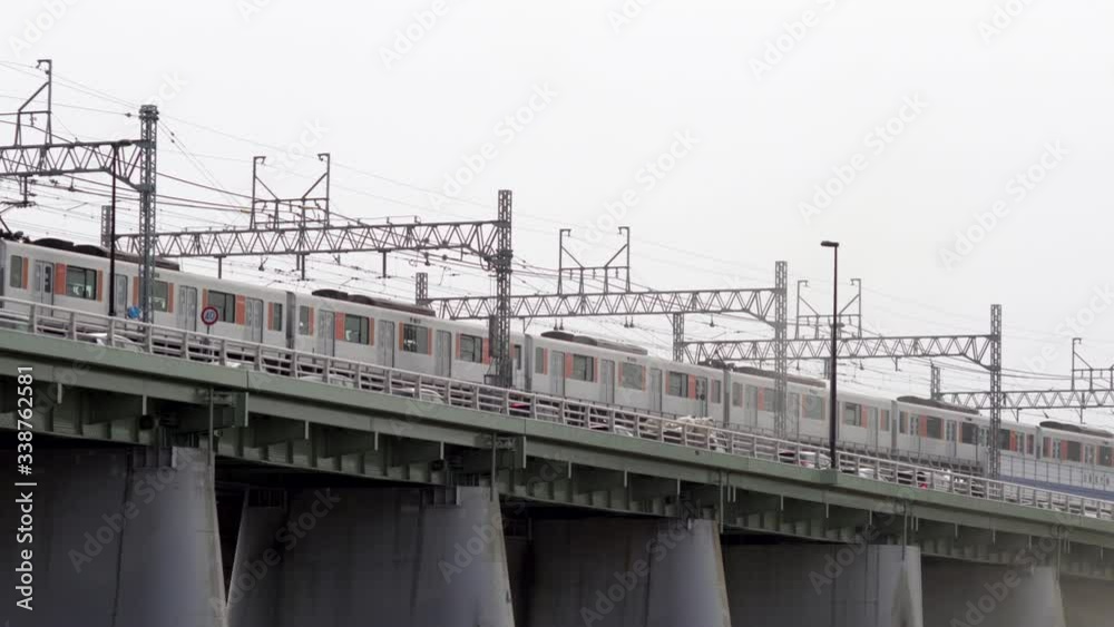 A Long Train Passing By On The Railway On The Bridge In Tokyo, Japan - Low Angle Shot A Long Train Passing By On The Railway On The Bridge In Tokyo, Japan - Low Angle Shot