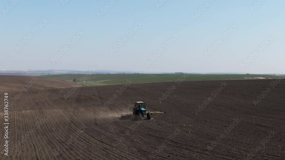 Aerial view blue tractor with a seeder goes across the field. Aerial view blue tractor with a seeder goes across the field.