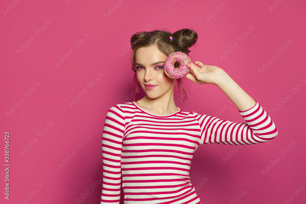 Happy woman holding donut on colorful pink background, diet concept Happy woman holding donut on colorful pink background, diet concept
