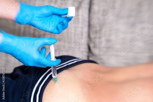 A doctor in medical gloves enters the medicine with a syringe to the patient. Intramuscular injection into the buttock.