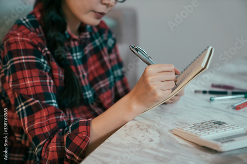 Фотография closeup view of woman's hand holding pen jotting down on notebook
