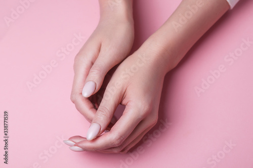 Elegant and graceful hands with slender graceful fingers is touching to each other on pink background