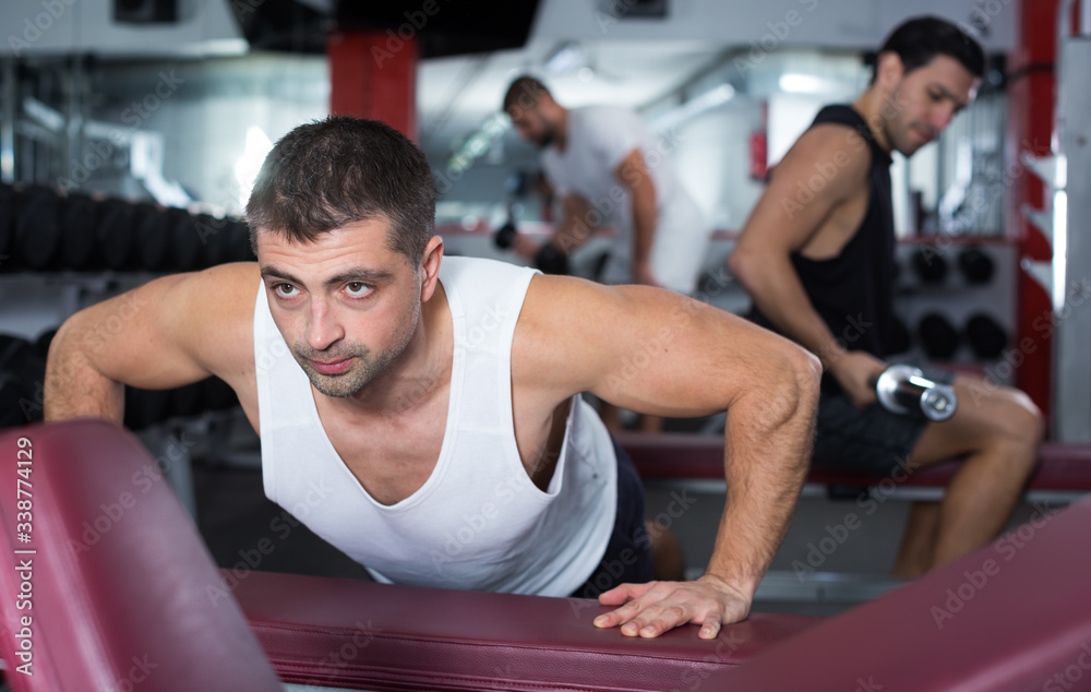 Naklejka premium Man doing incline push-ups in gym