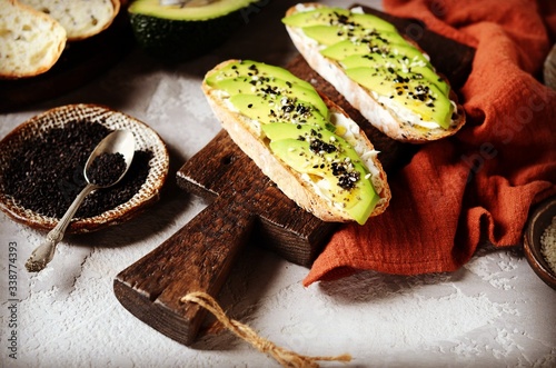 Sandwich with avocado, curd cheese, chia seeds and sesame seeds on a gray background