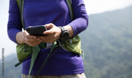 Successful hiker using smartphone on mountain top