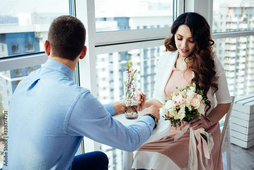 Love story. Newlyweds are sitting at the table in a cafe. The bride with a wedding bouquet. Happiness. Relationship. Real love. Lifestyle. Just married. Love story. Newlyweds are sitting at the table in a cafe. The bride with a wedding bouquet. Happiness. Relationship. Real love. Lifestyle. Just married.