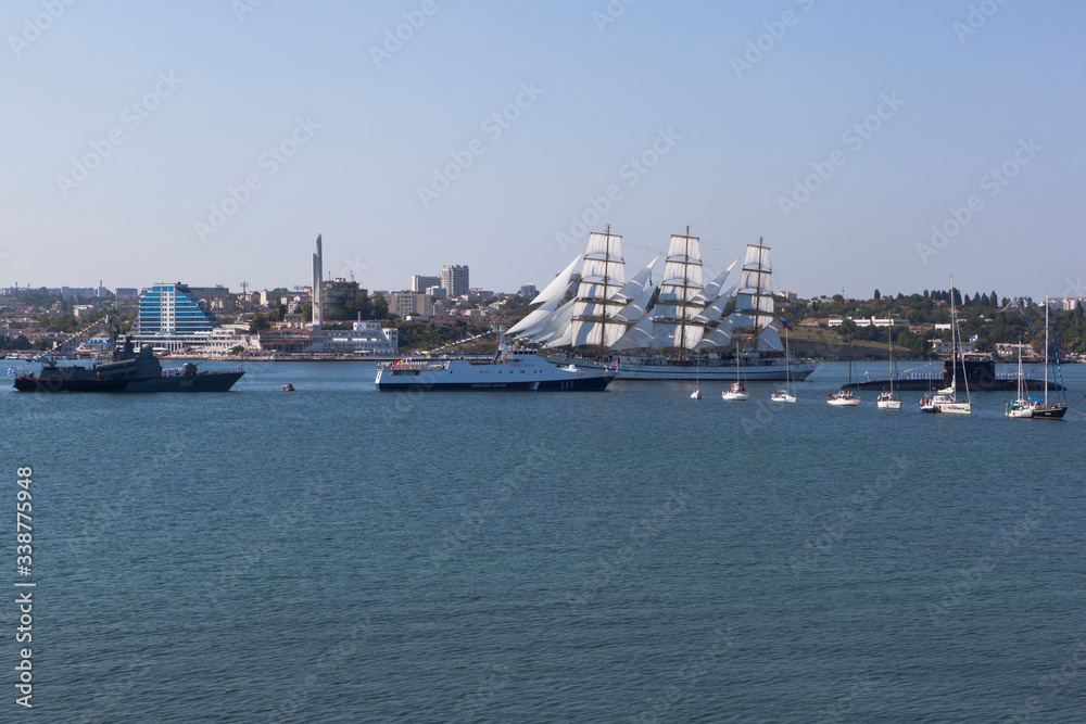 Khersones sailboat passes near the parade system of warships at the Navy Day parade in Sevastopol Bay, Crimea