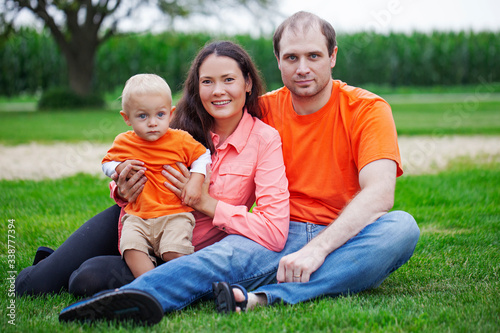 Portrait of happy family with little son sitting on grass