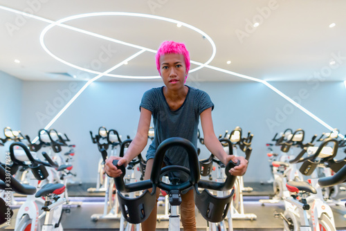 Young rebellious Asian woman with pink hair at the gym