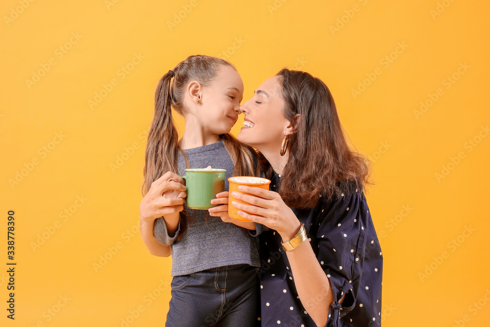 Woman and her little daughter with tasty cocoa drink on color background Woman and her little daughter with tasty cocoa drink on color background