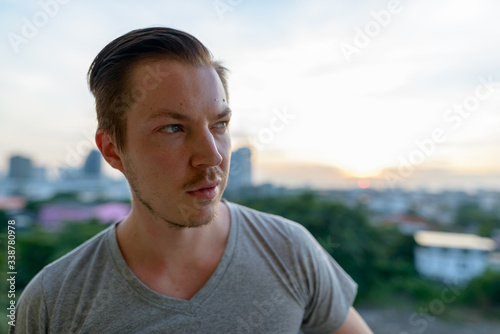 Face of young handsome man thinking against view of the city
