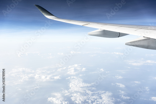 Passenger plane flying above the clouds. View from the wing of the plane.