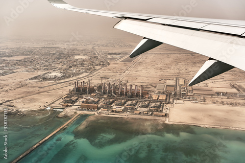 Passenger plane flying over the coast of Qatar. View from the wing of the plane with the bottom of a desalination plant.