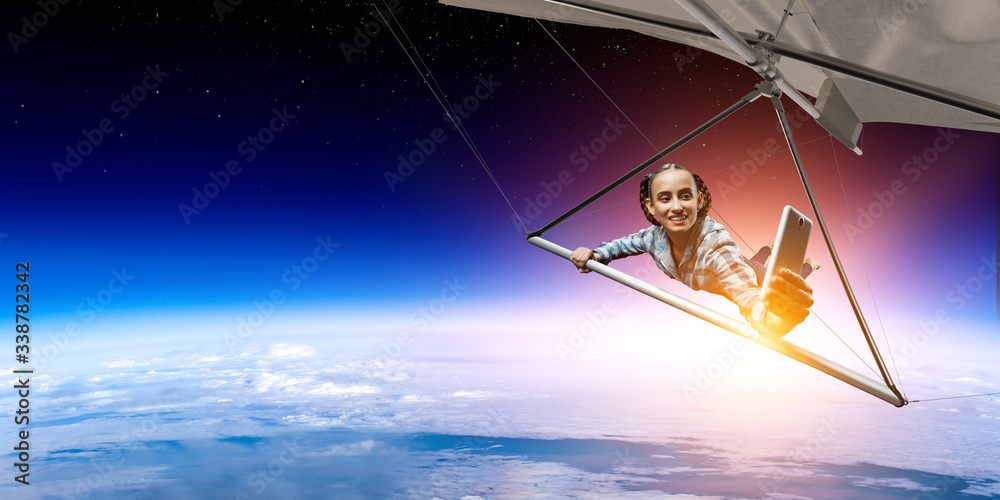 Young woman flying on hang glider. Mixed media