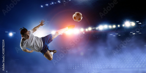 Football player on stadium jumps to kick a ball © Sergey Nivens