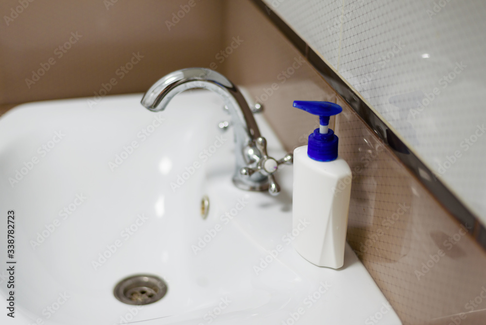 A bottle of soap on the white sink in the bathroom. A bottle of soap on the white sink in the bathroom.