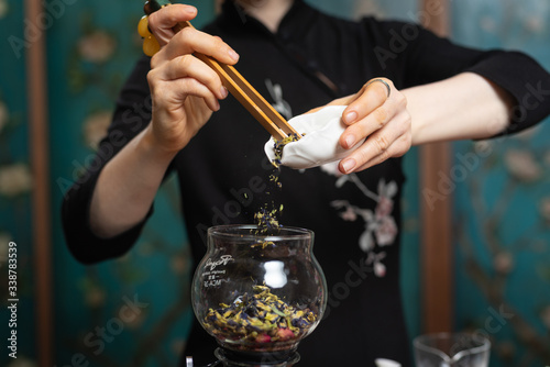  Tea ceremony. Girl pours tea leaf into a glass flask.